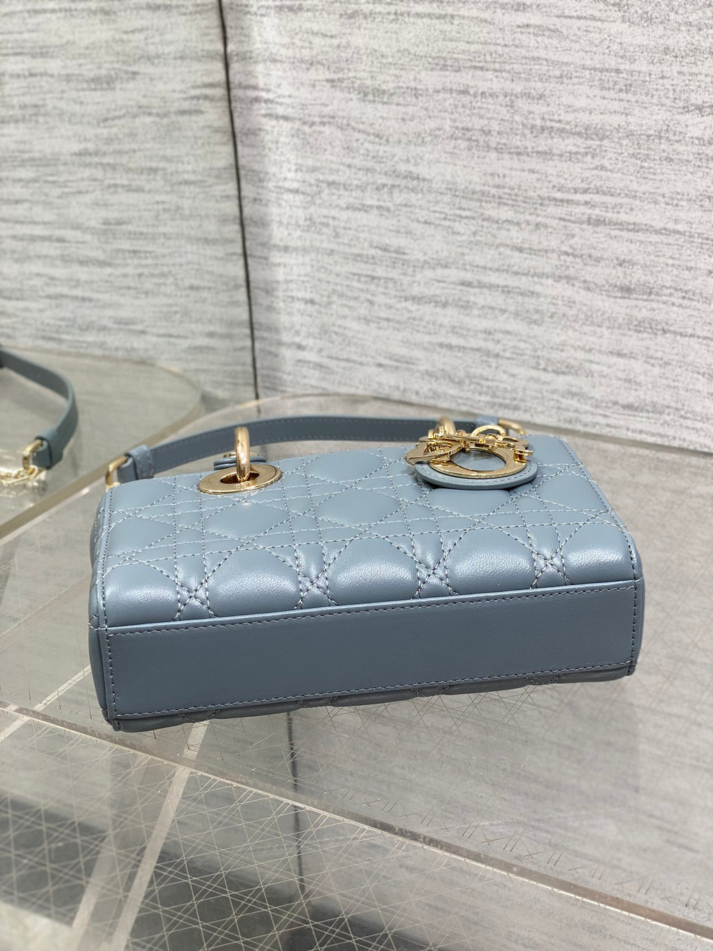 Dior quilted handbag top view in powder blue with loop handle and gold chain detail