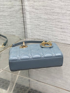 Dior quilted handbag top view in powder blue with loop handle and gold chain detail