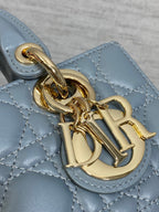 Dior handbag charm with gold linked hardware and metal D emblem on blue quilted leather
