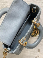 Dior quilted handbag close-up with open top, gold clasp, and blue leather lining