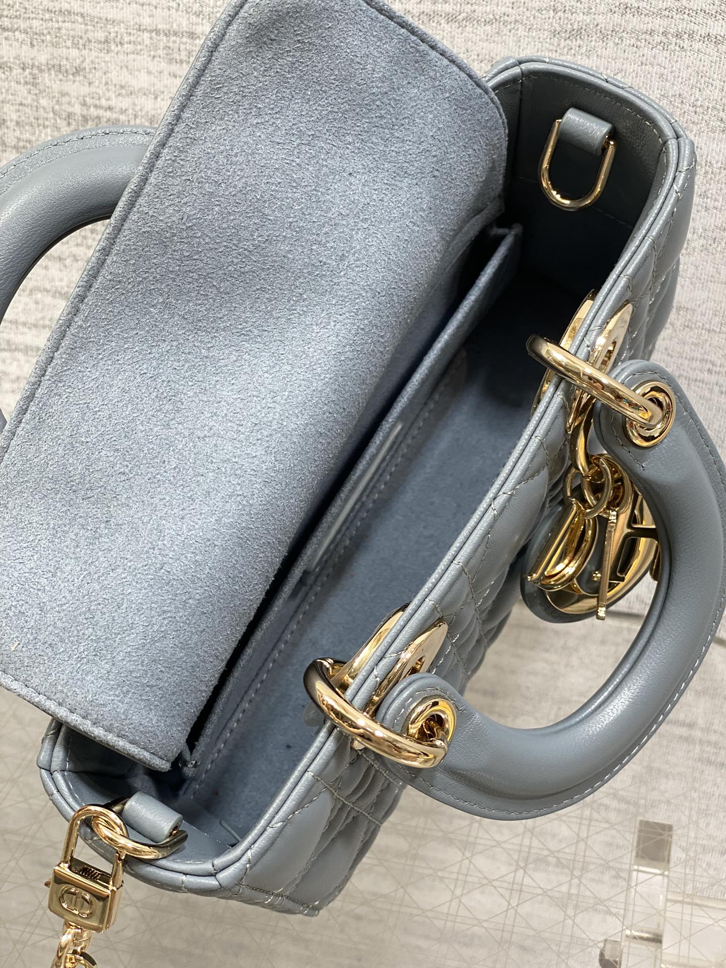 Dior quilted handbag close-up with open top, gold clasp, and blue leather lining