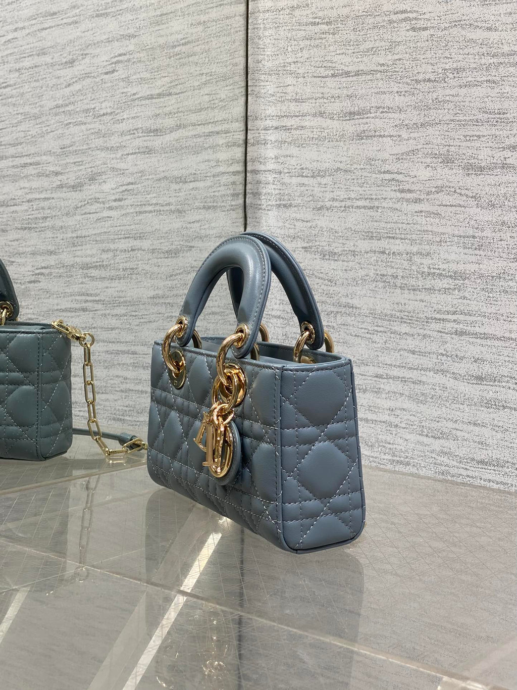 Dior quilted handbag side view in powder blue with gold hardware and chain strap