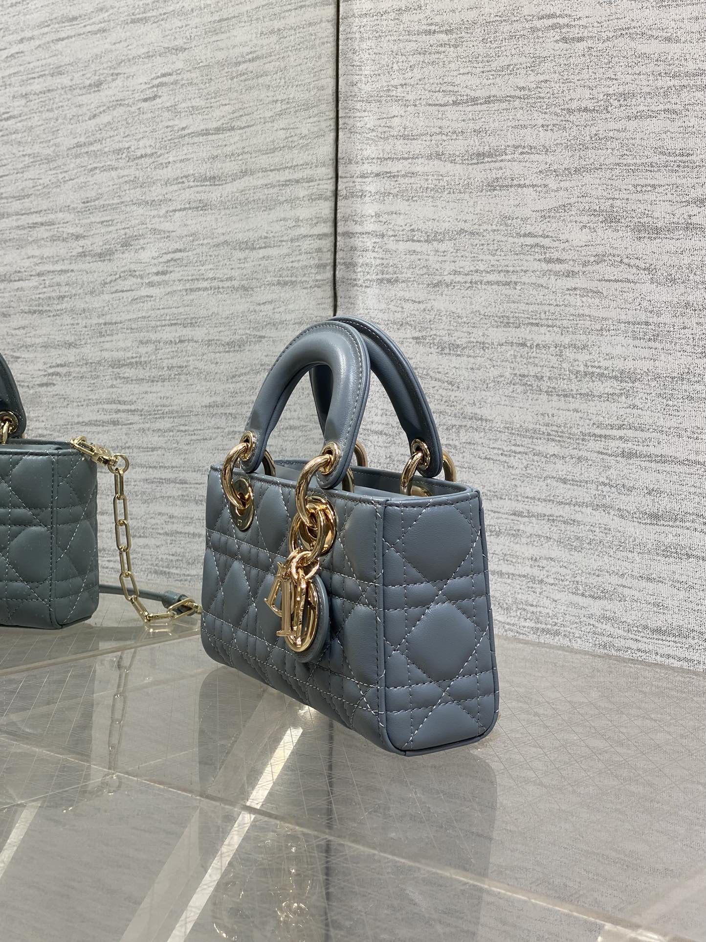 Dior quilted handbag side view in powder blue with gold hardware and chain strap