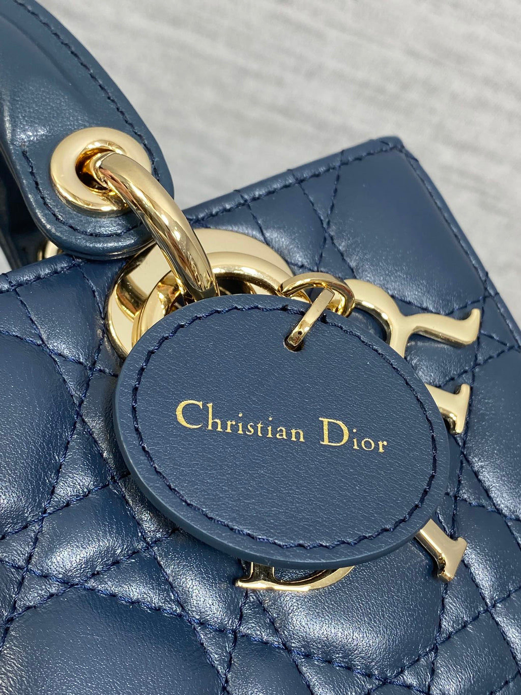 Dior handbag close-up of gold charm clasp and embossed Christian Dior text on leather