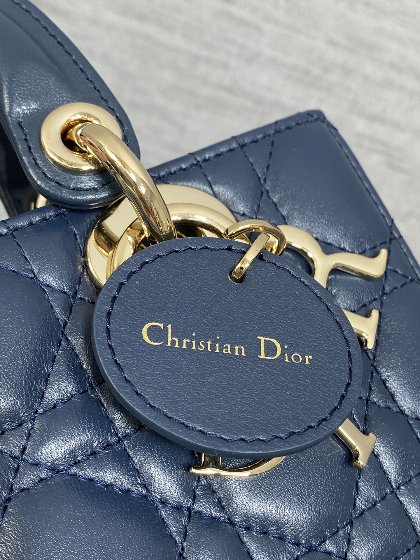 Dior handbag close-up of gold charm clasp and embossed Christian Dior text on leather