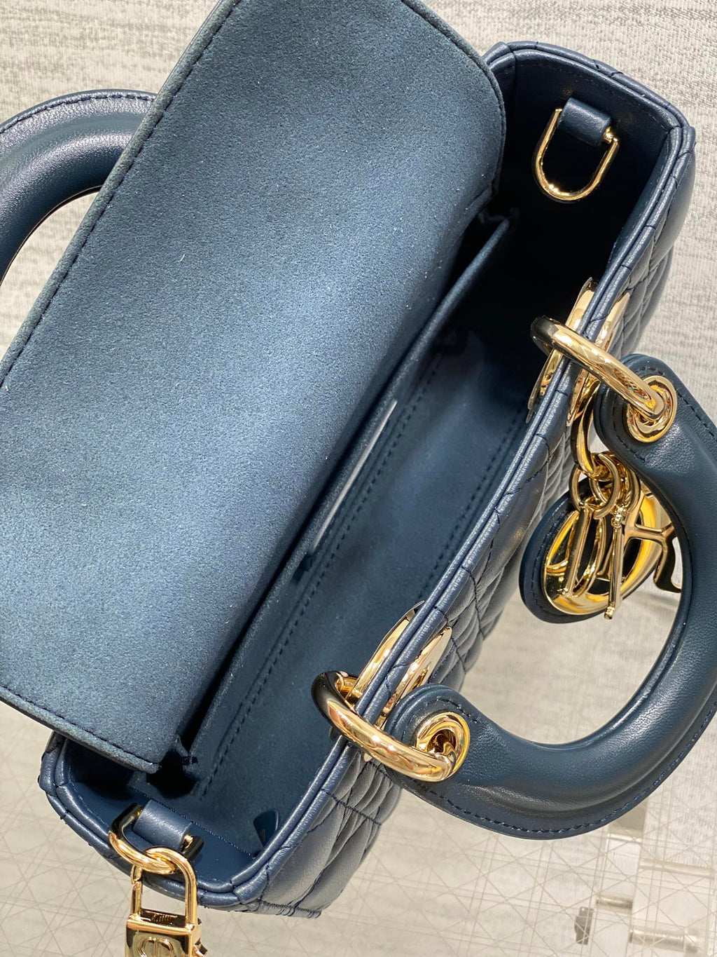 Dior handbag side view in navy leather with gold-tone hardware and hinged top