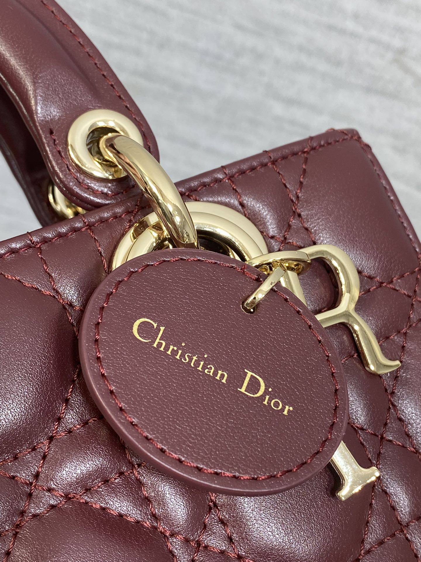 Dior logo medallion on burgundy leather strap with gold-tone hardware