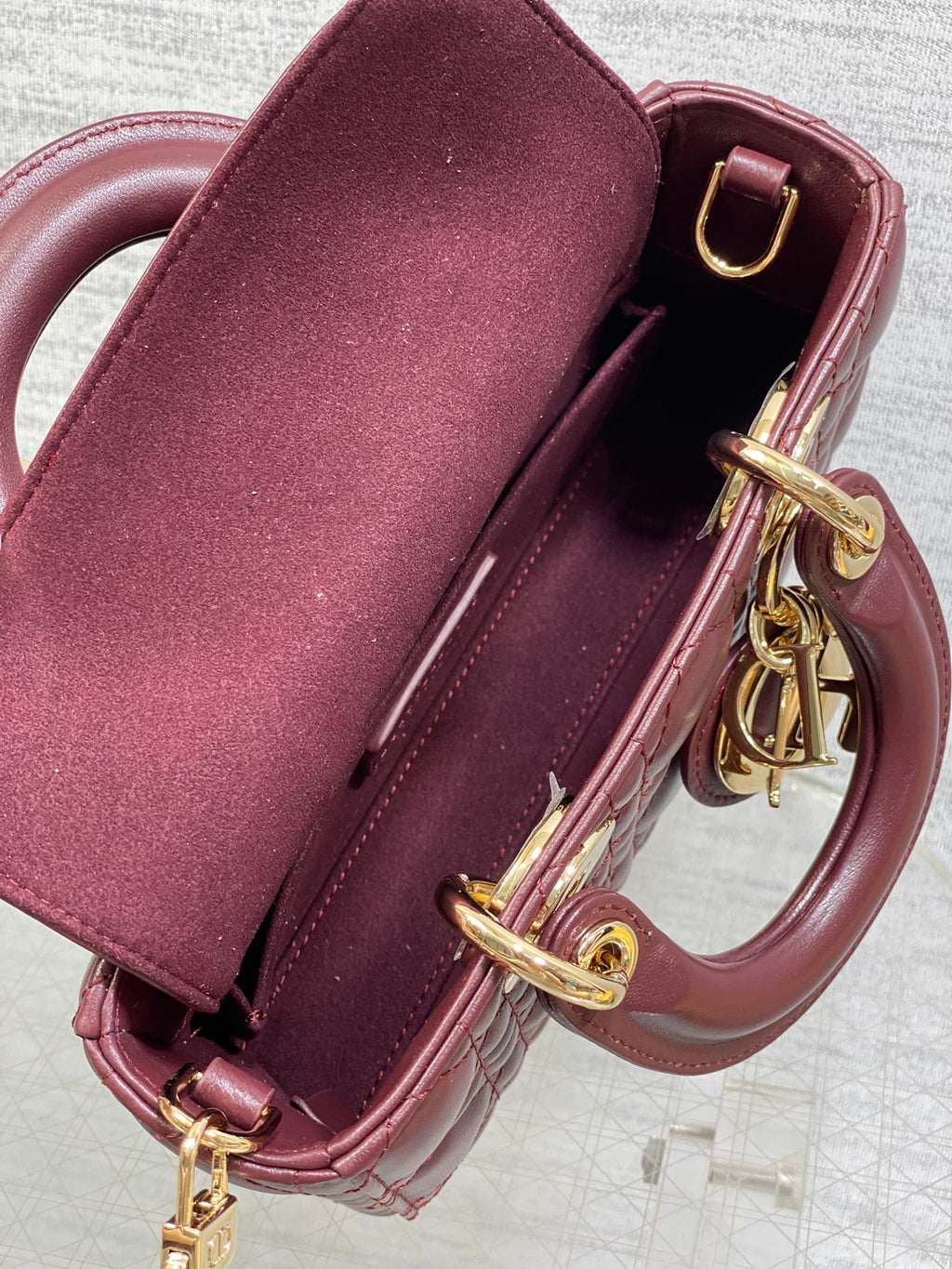 Dior mini handbag open top showing burgundy interior, gold rings and clasp hardware