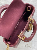 Dior mini handbag open top showing burgundy interior, gold rings and clasp hardware