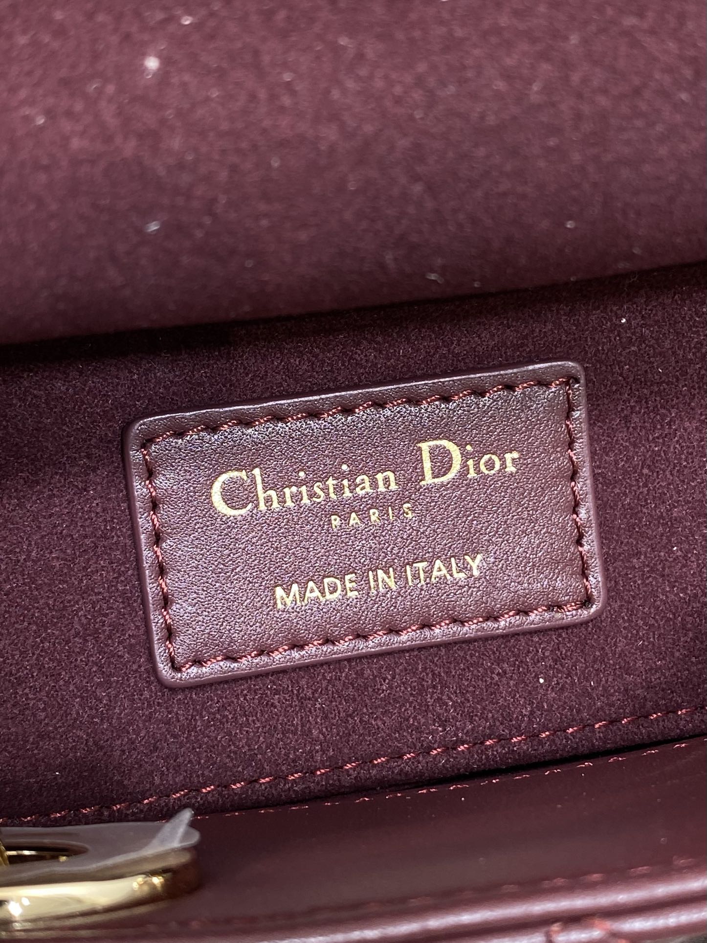 Dior leather label on burgundy bag reading “Christian Dior” and “Made in Italy”