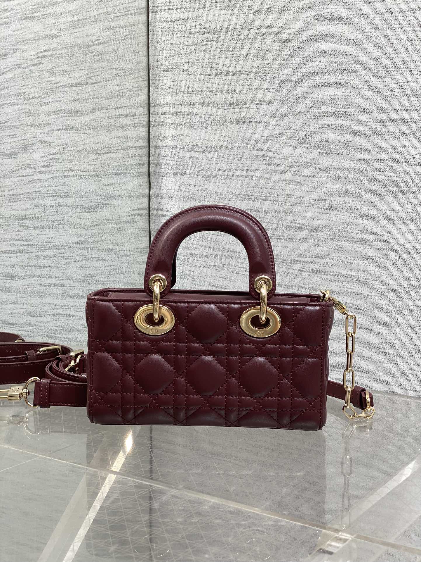 Dior quilted handbag side view with burgundy leather and crossbody strap, gold hardware