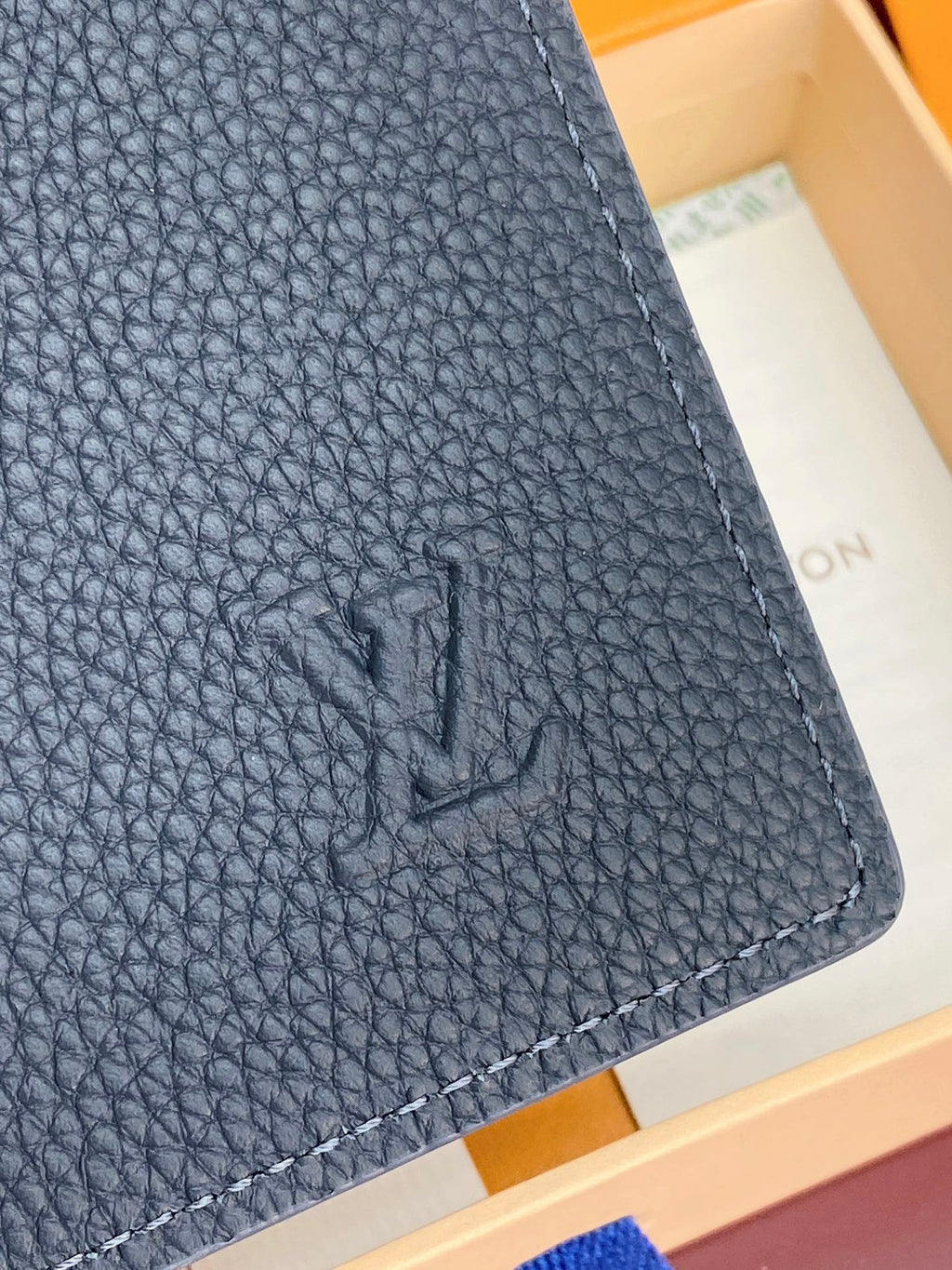 Close-up Louis Vuitton leather card holder corner, dark blue pebble texture