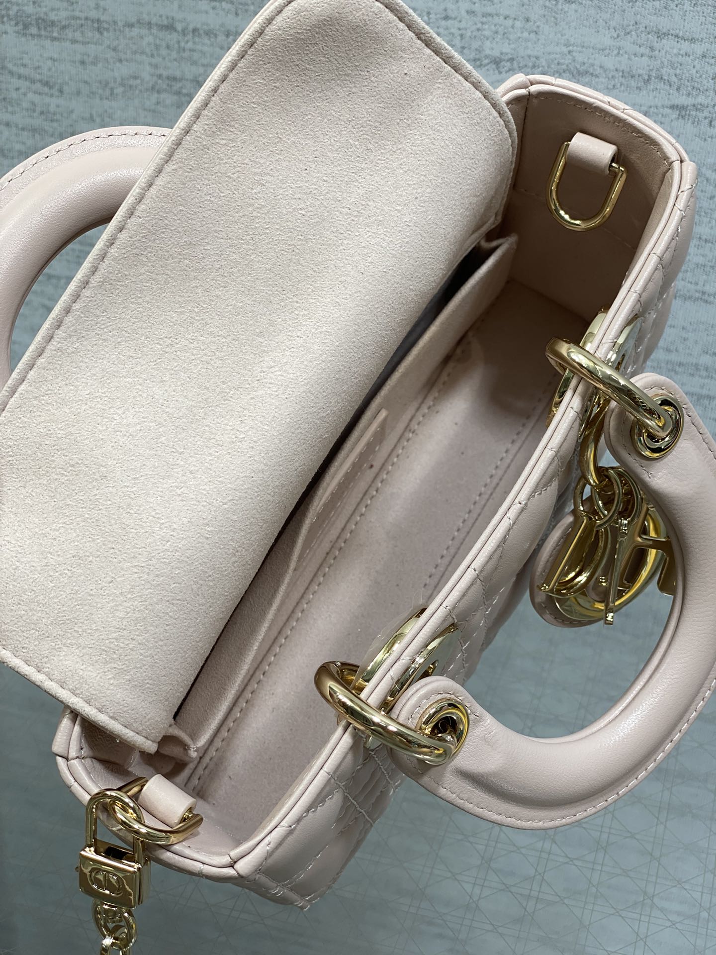 Light pink Dior bag interior with leather strap and gold clasp hardware
