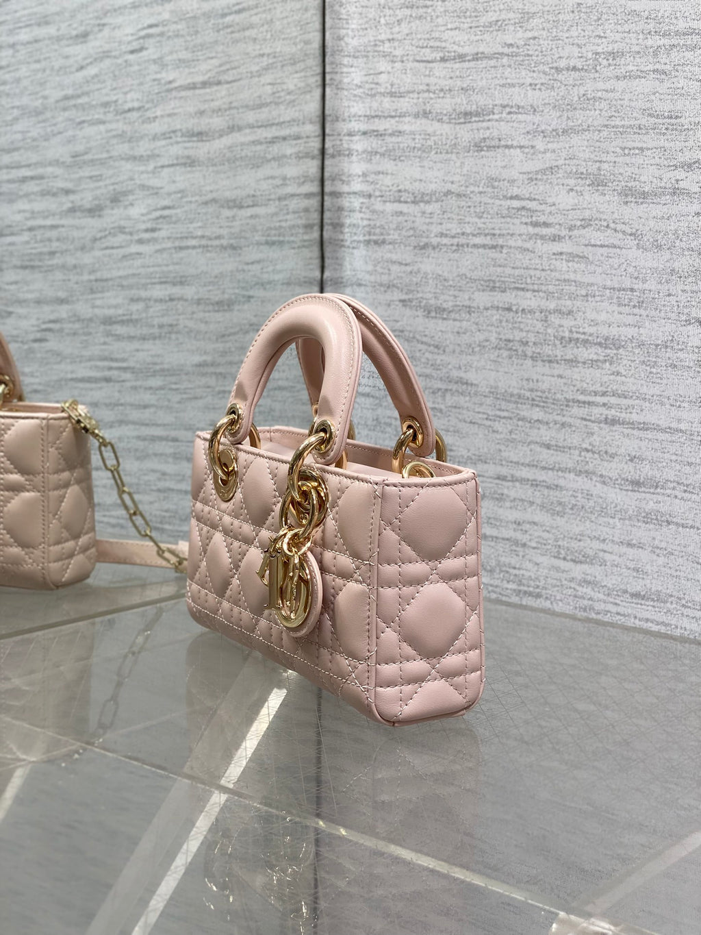 Pink quilted Dior bag side view with top handle and gold chain strap