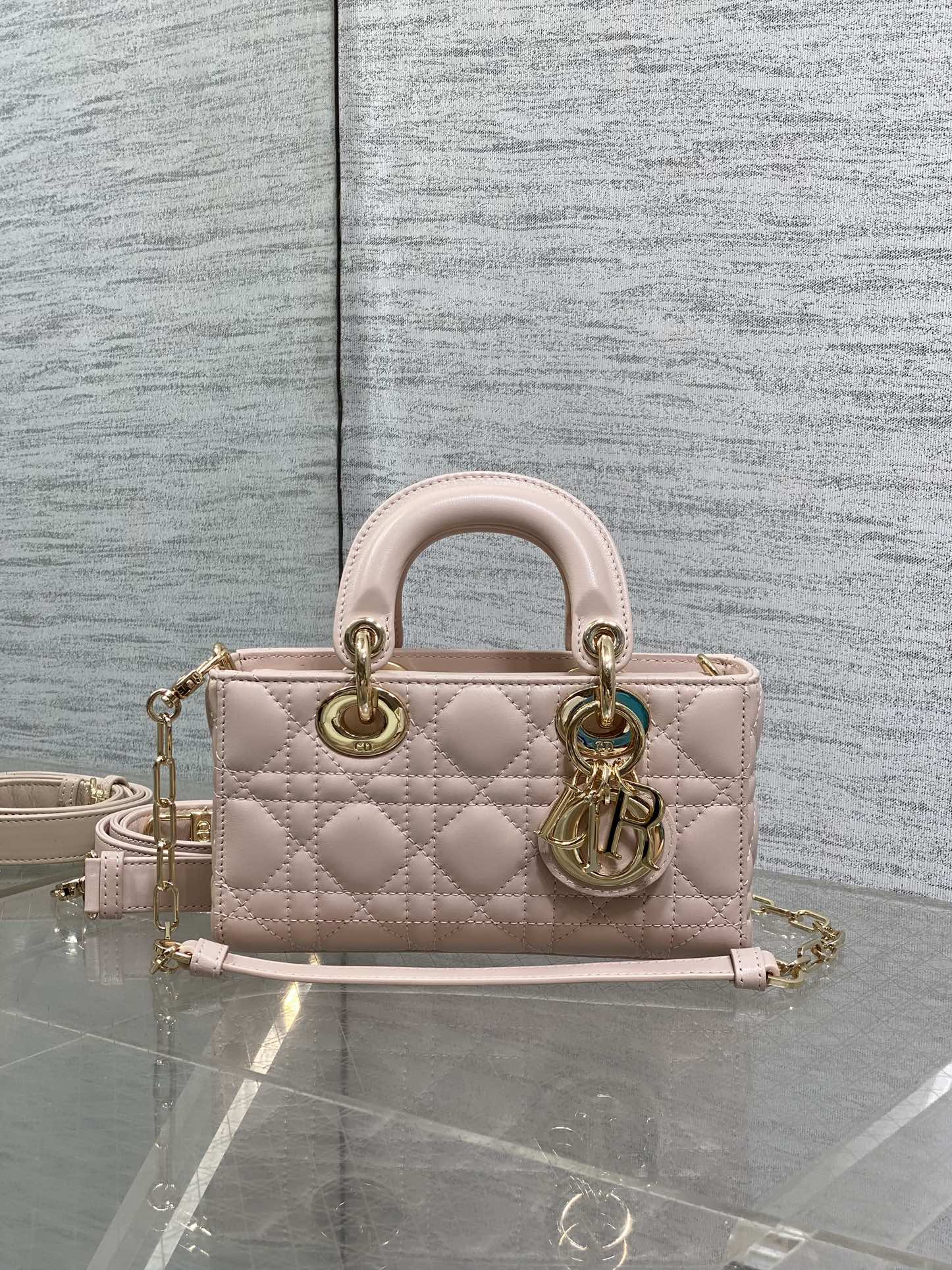 Pink quilted Dior bag with handles and adjustable shoulder strap, gold hardware