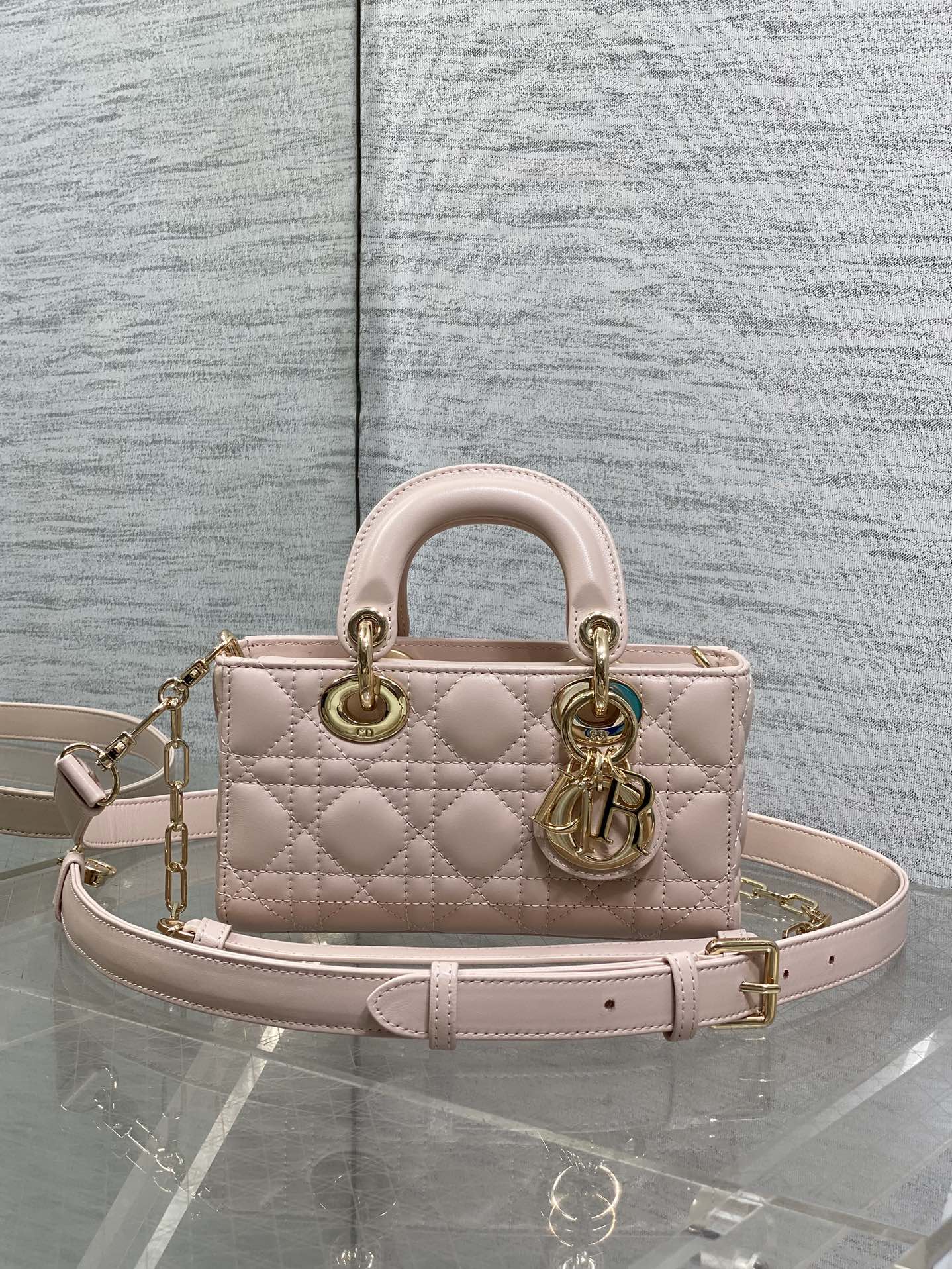 Pink quilted Dior bag with top handles, gold hardware and chain shoulder strap
