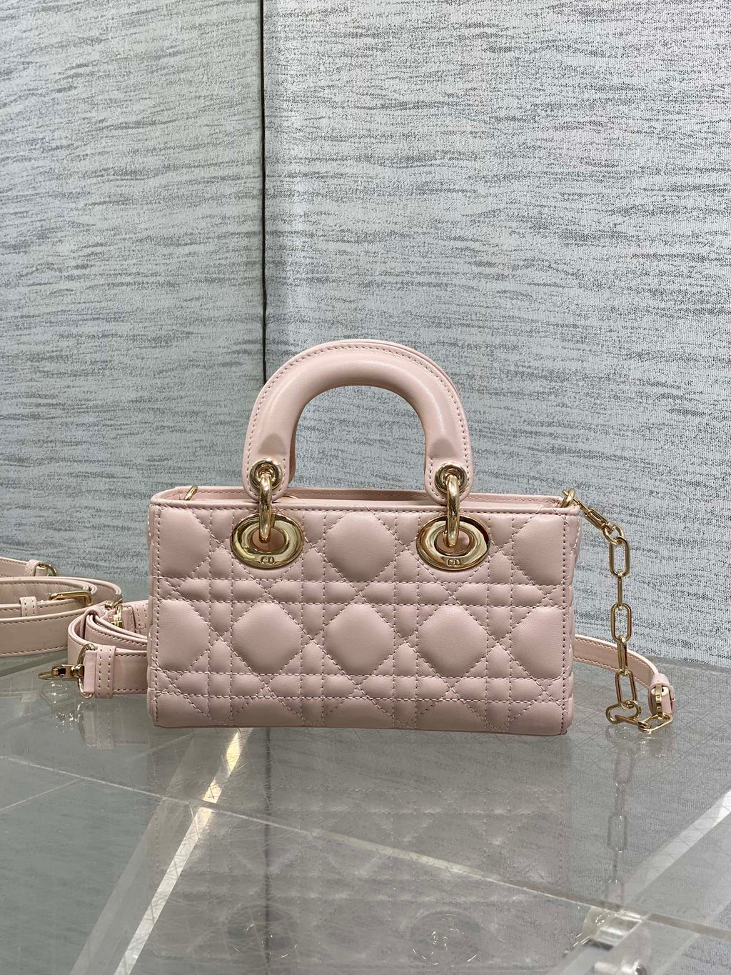 Pink quilted Dior handbag with top handles and gold chain shoulder strap, front view