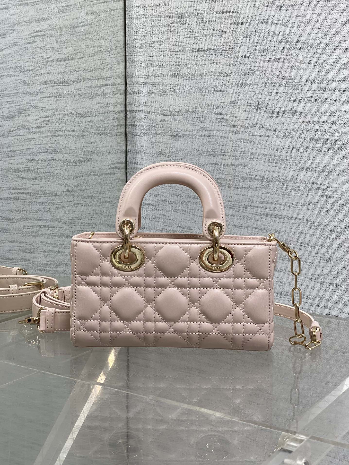 Pink quilted Dior handbag with top handles and gold chain shoulder strap, front view