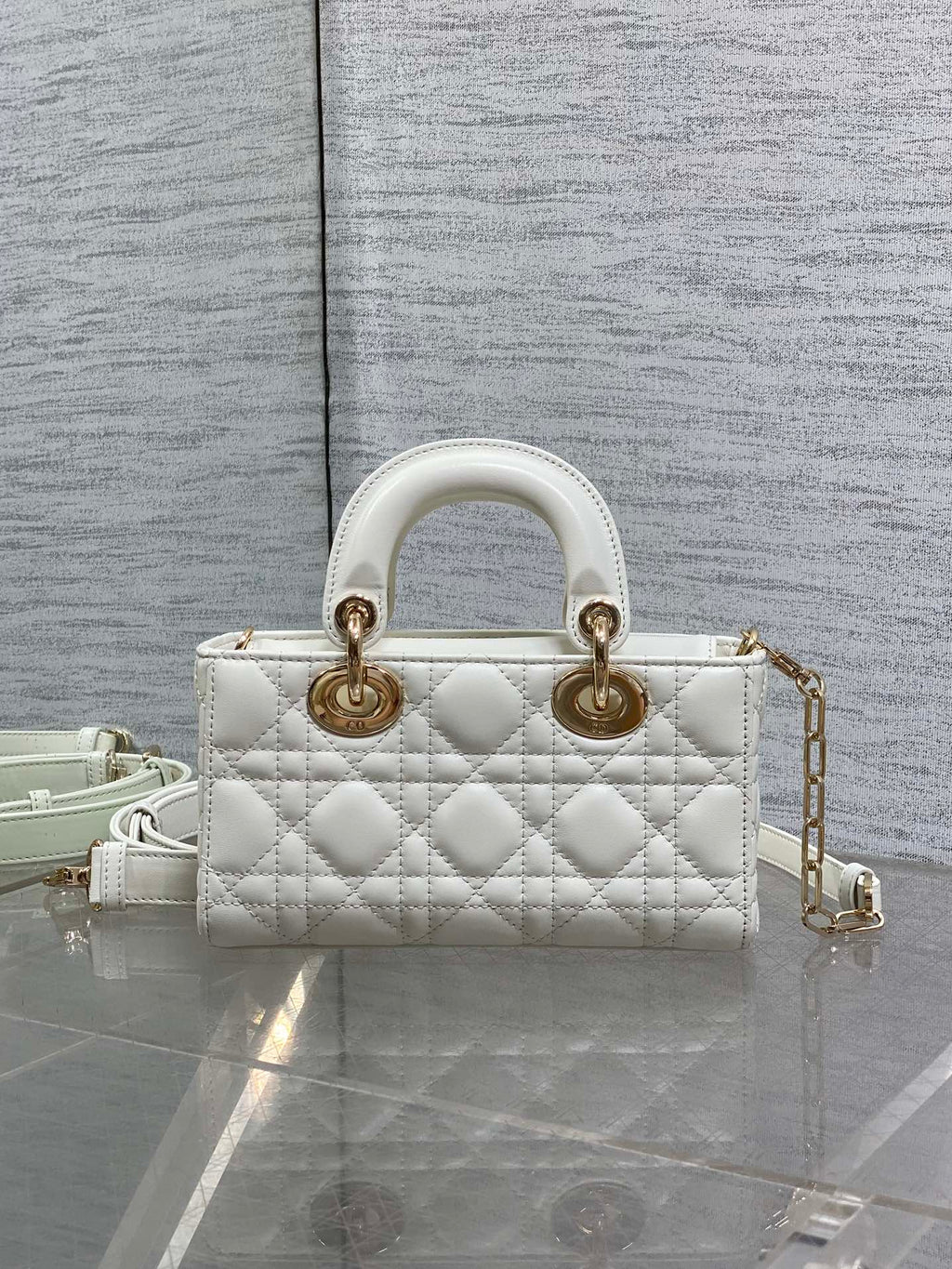 Quilted white handbag with two top handles, gold hardware, and adjustable crossbody strap