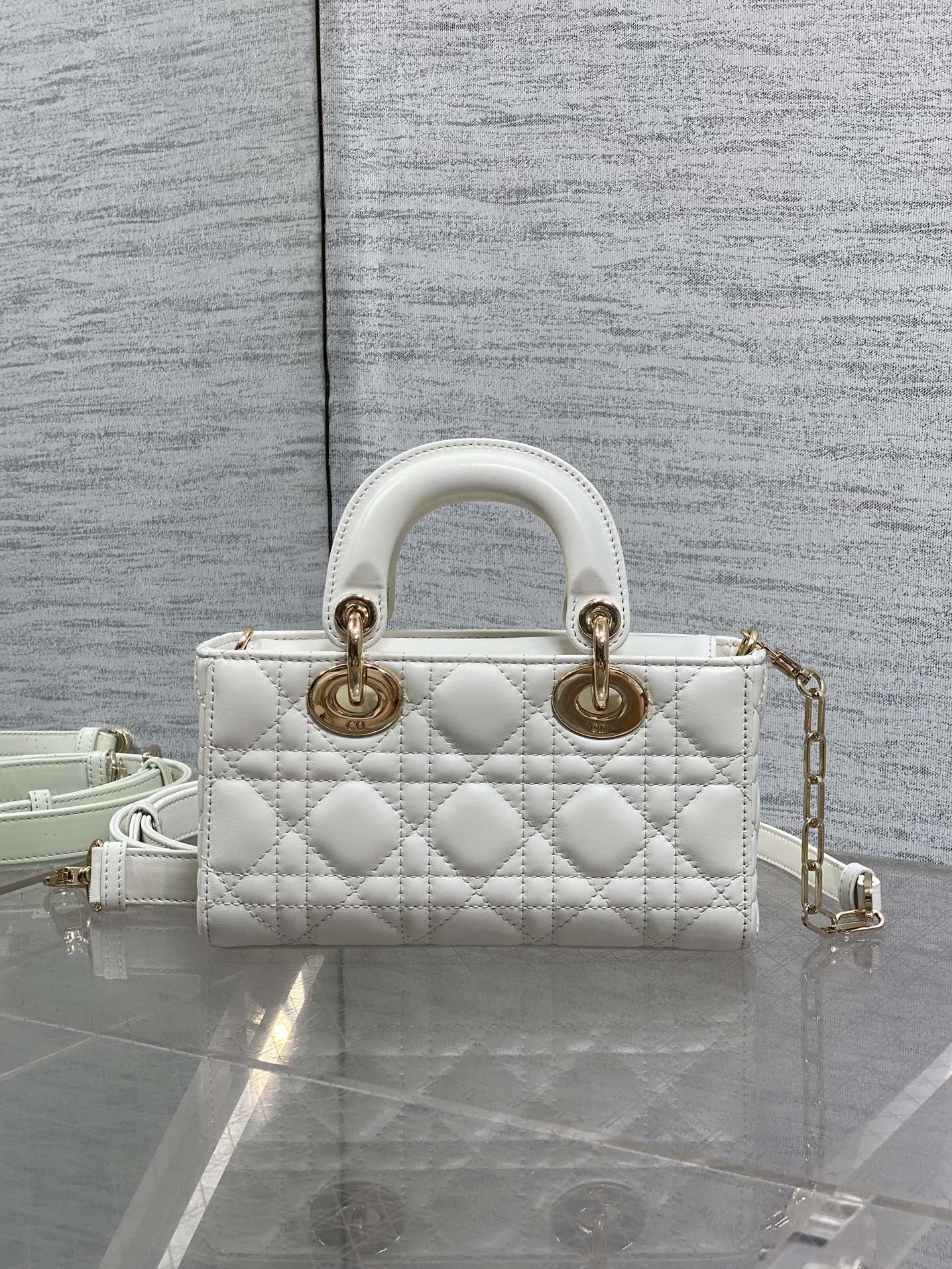 Quilted white handbag with two top handles, gold hardware, and adjustable crossbody strap
