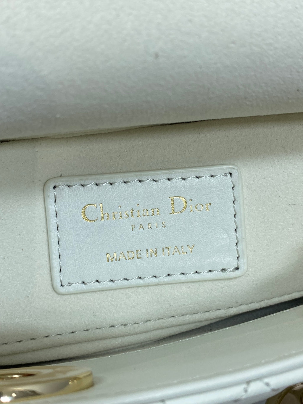 White handbag leather tag reading "Christian Dior" and "Made in Italy"