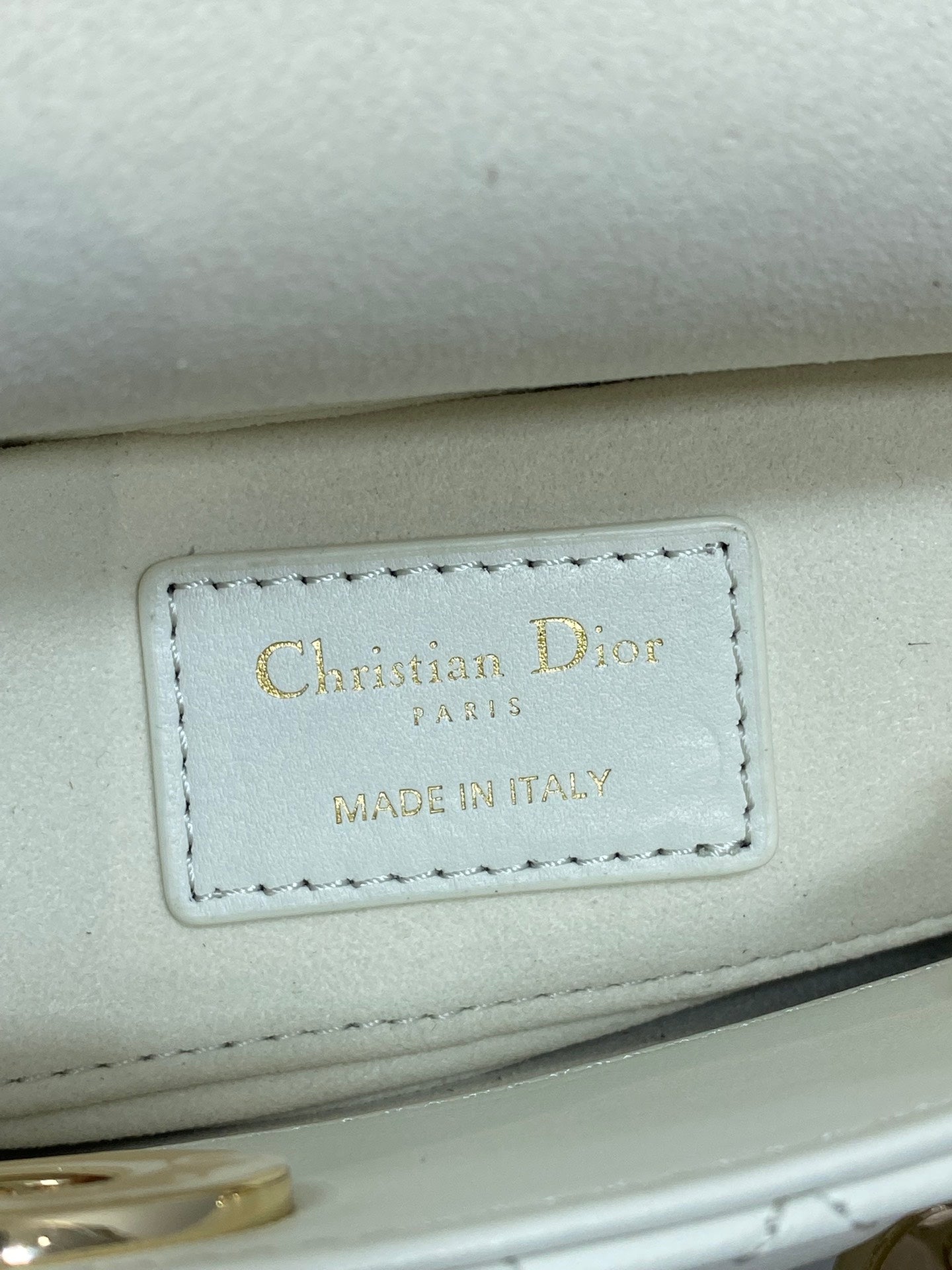 White handbag leather tag reading "Christian Dior" and "Made in Italy"