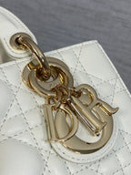 White quilted handbag detail with gold chain link hardware and Dior charm