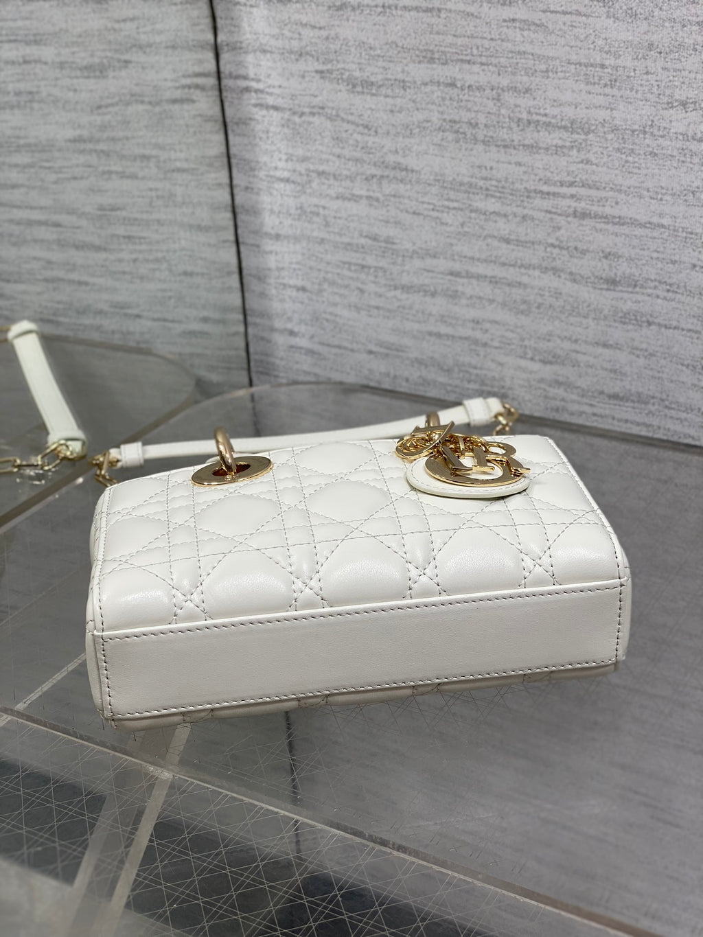 White quilted shoulder bag with gold hardware, short strap, and top handle