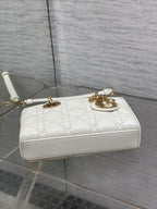 White quilted shoulder bag with gold hardware, short strap, and top handle