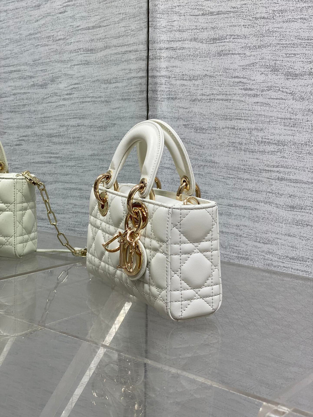 Quilted white handbag side view with top handles and gold-tone chain shoulder strap