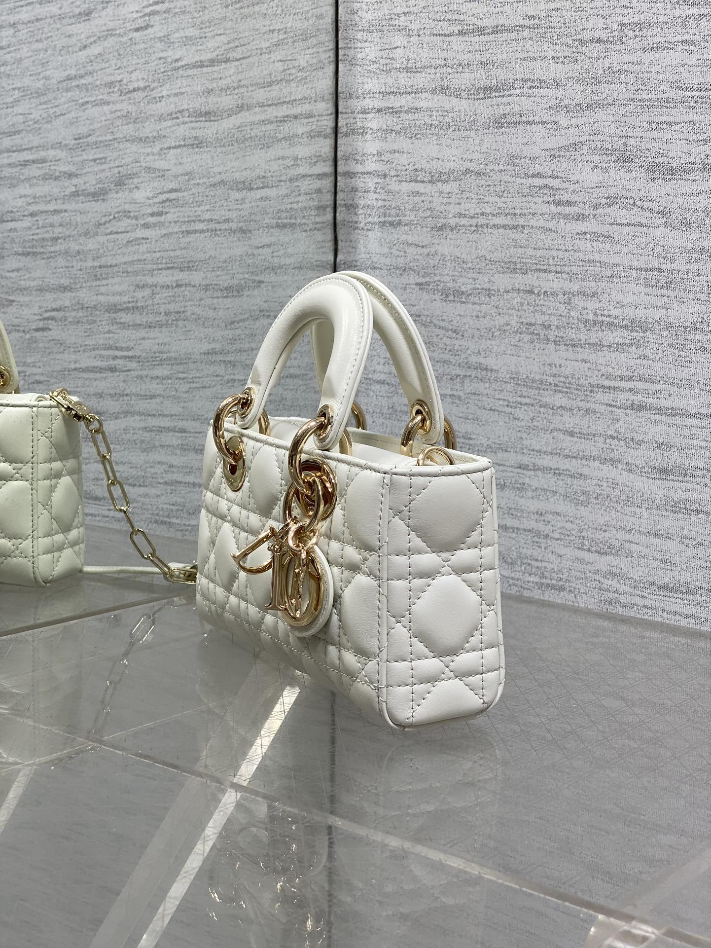 Quilted white handbag side view with top handles and gold-tone chain shoulder strap