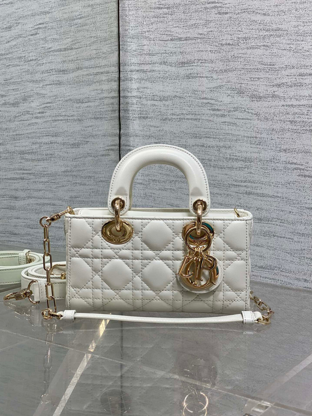 Quilted white handbag with gold-tone hardware, top handles, and long crossbody strap