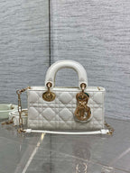 Quilted white handbag with gold-tone hardware, top handles, and long crossbody strap