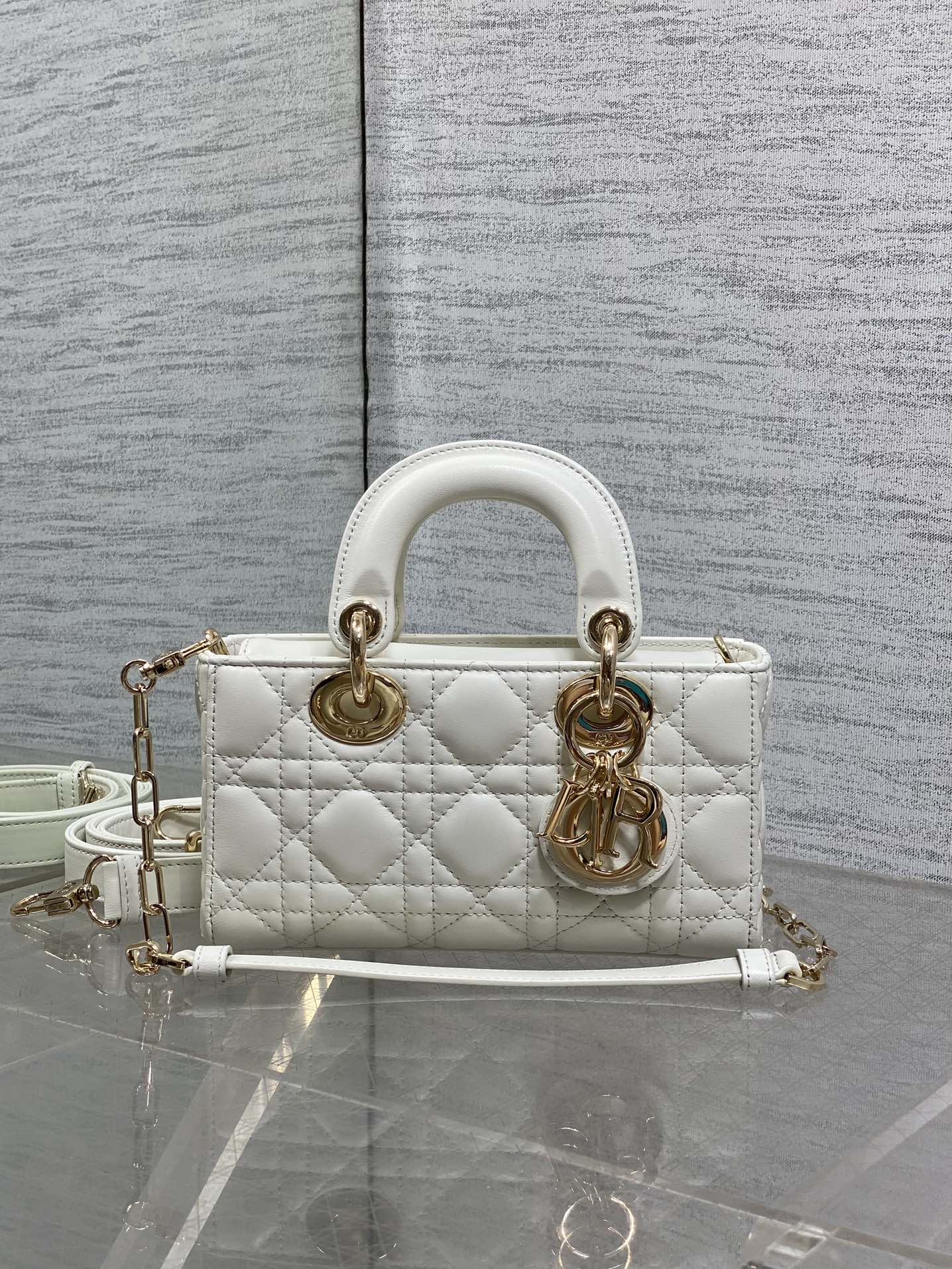 Quilted white handbag with gold-tone hardware, top handles, and long crossbody strap