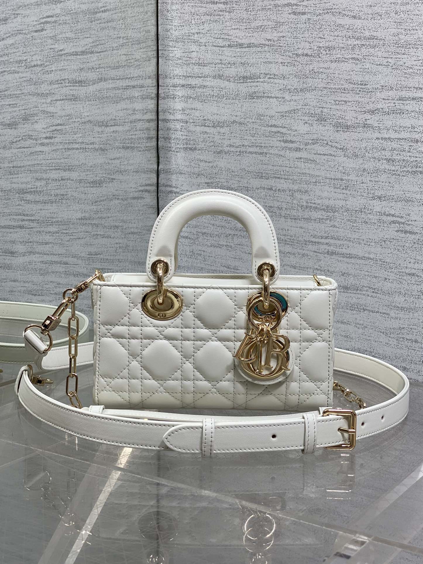 Dior quilted handbag in white with top handles, gold hardware, and a crossbody strap
