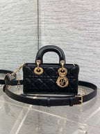 Dior quilted handbag in dark leather with top handles, gold logo charm, and crossbody strap