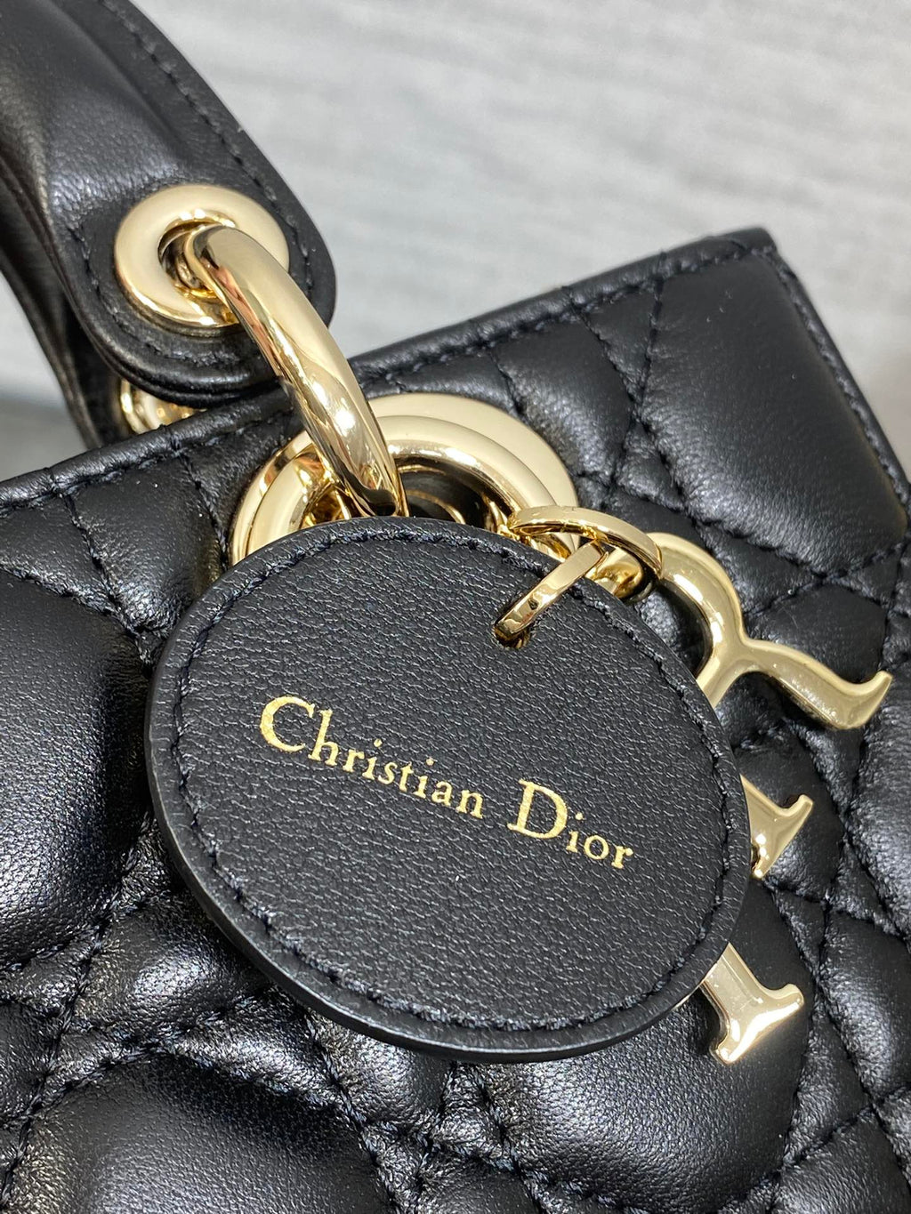 Dior handbag charm detail with round leather tag reading Christian Dior