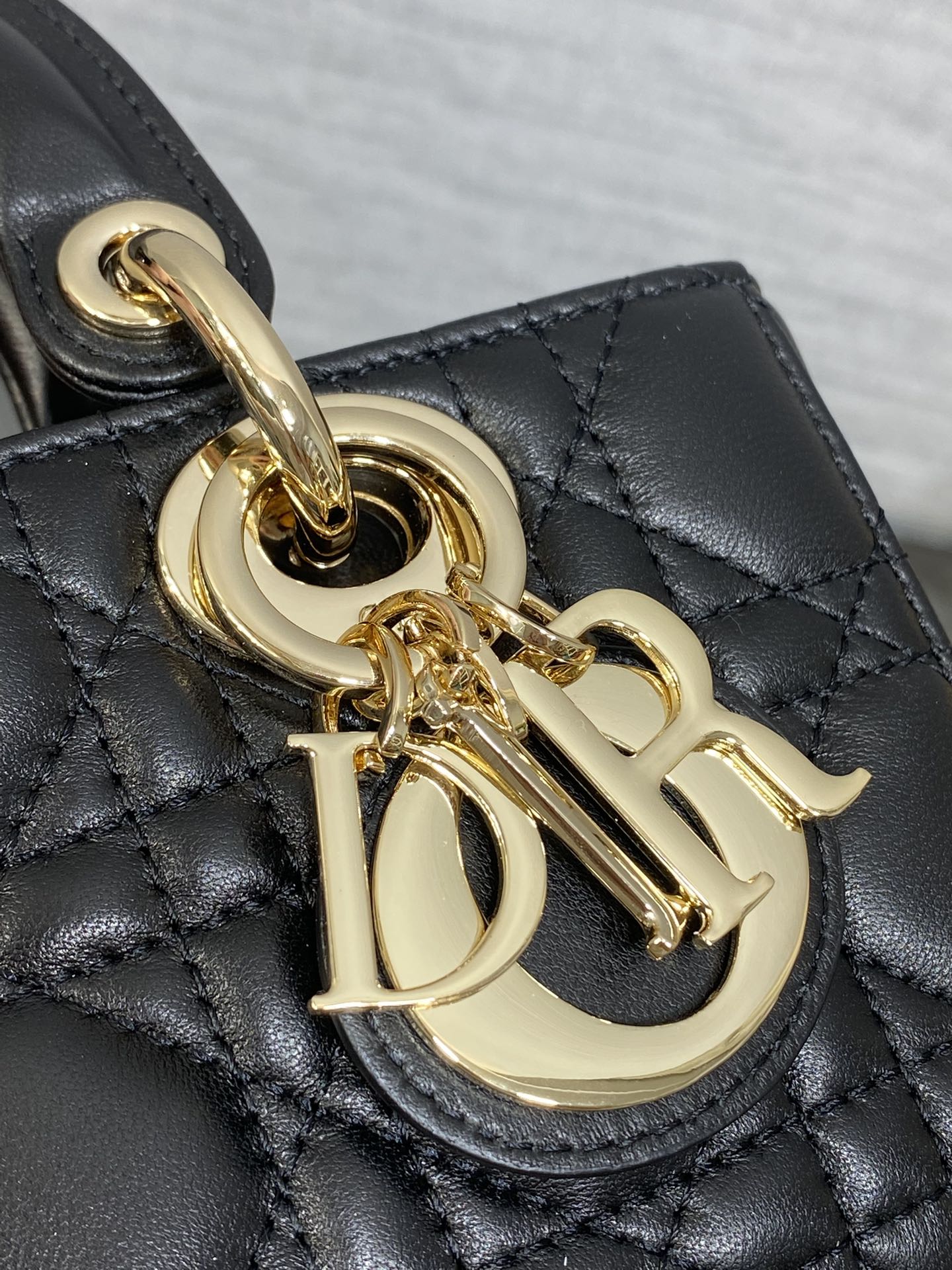 Dior handbag detail with gold CD clasp charm on quilted dark leather