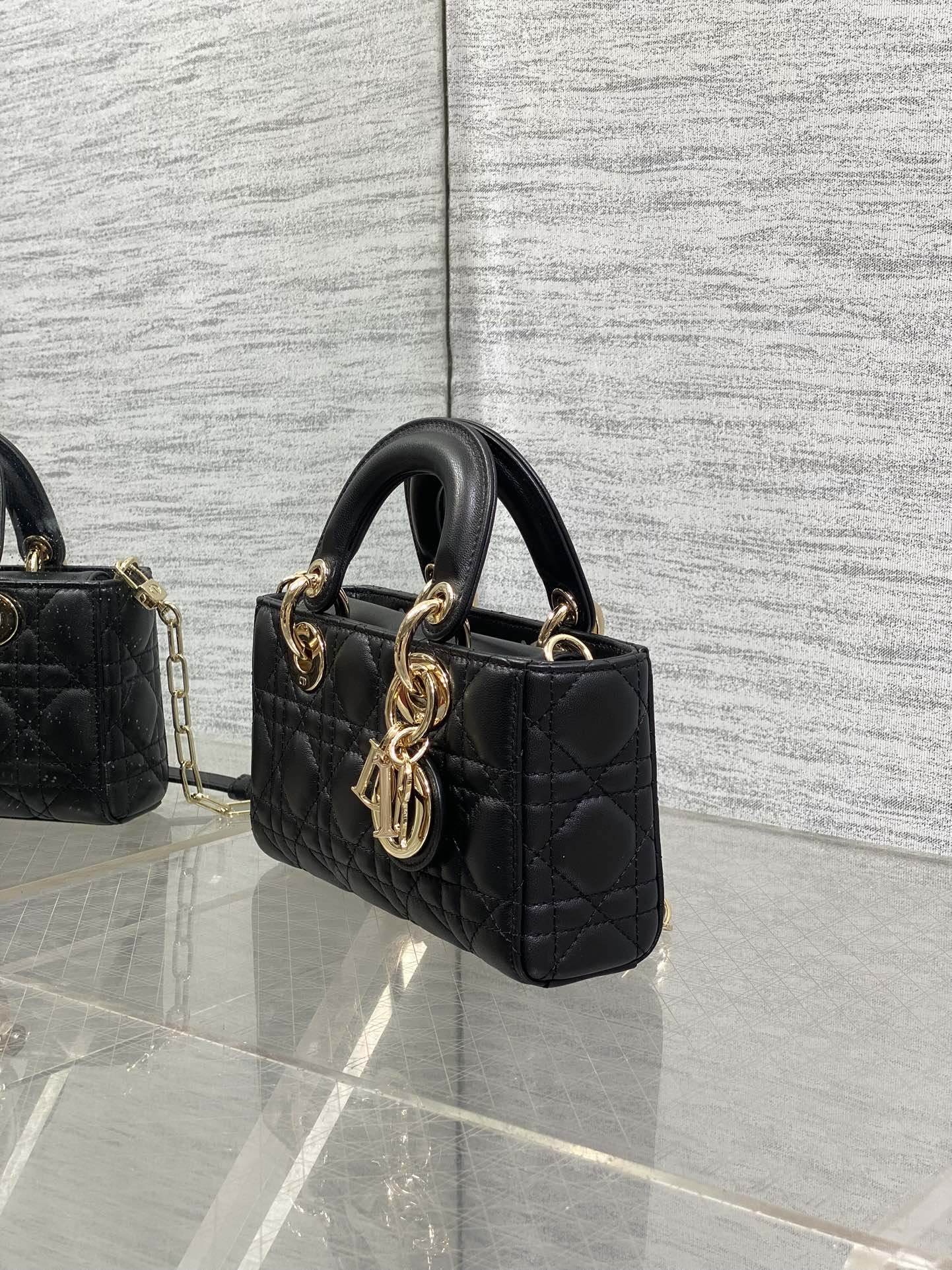 Dior quilted mini handbag side view with top handle, gold hardware, and long shoulder strap