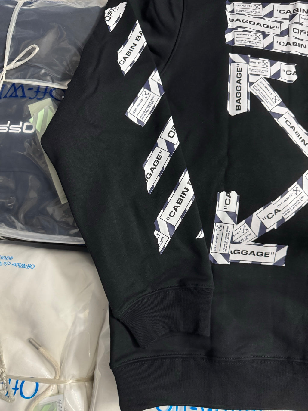 Black hoodie front with CABIN BAGGAGE graphic, sleeve stripe, and ribbed hem