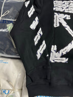 Black hoodie shoulder and sleeve with CABIN BAGGAGE repeating text print, laid on bag.