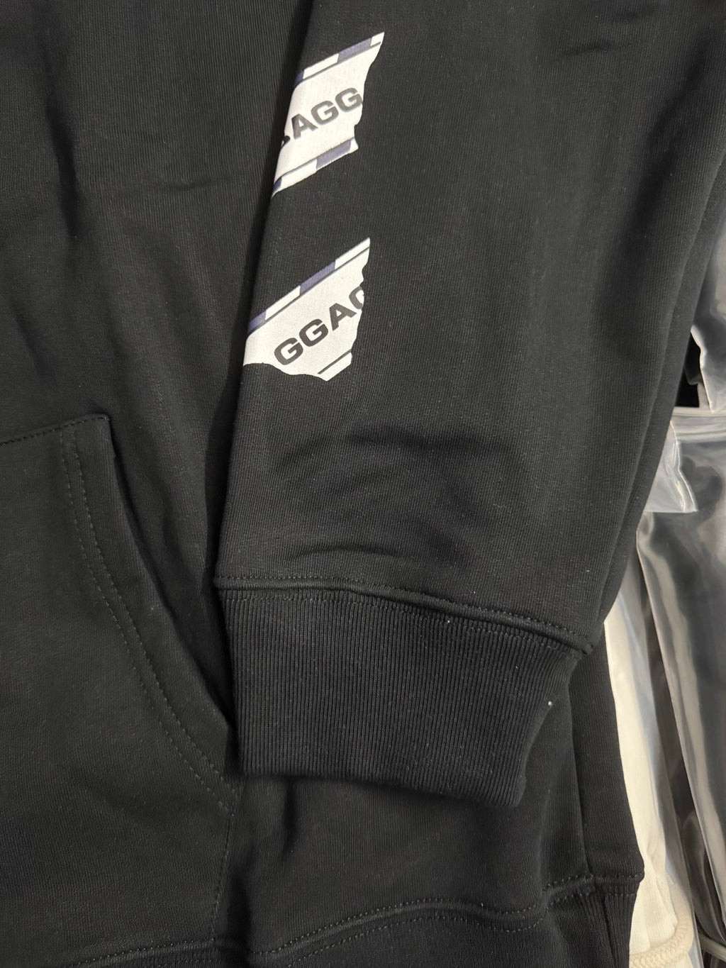 Black hoodie cuff and hem with printed CABIN BAGGAGE label stripe
