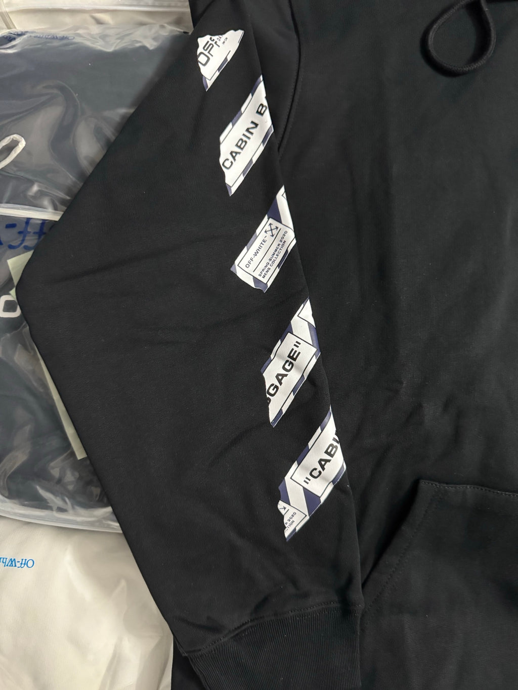 Black hoodie sleeve with vertical CABIN BAGGAGE label stripe