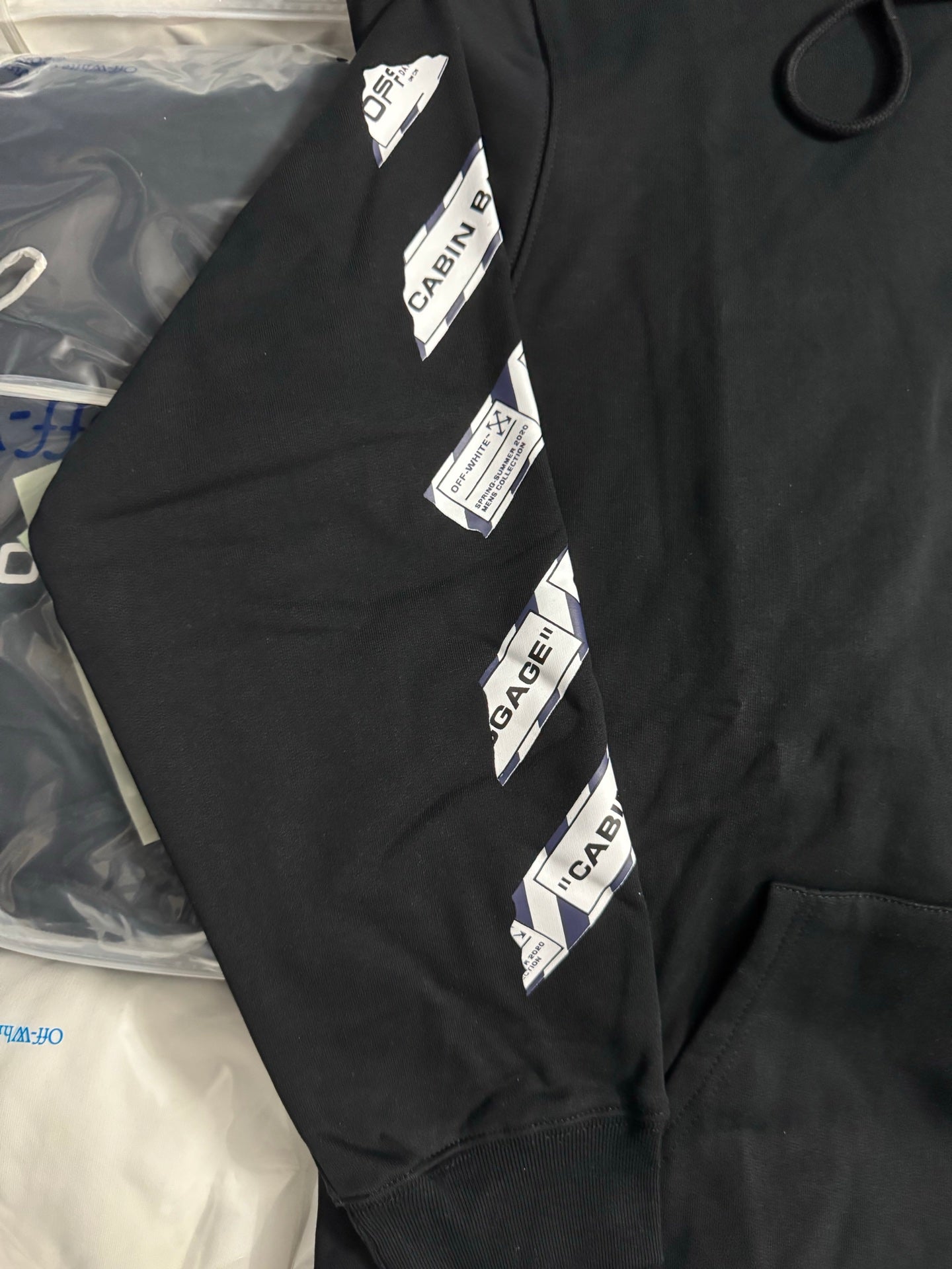 Black hoodie sleeve with vertical CABIN BAGGAGE label stripe