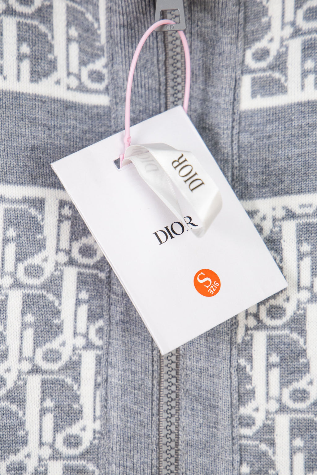 Grey knit zip jacket close-up with monogram trim and Dior brand tag