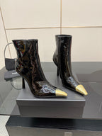 Pair of black patent ankle boots with tall heel and pointed gold toe caps