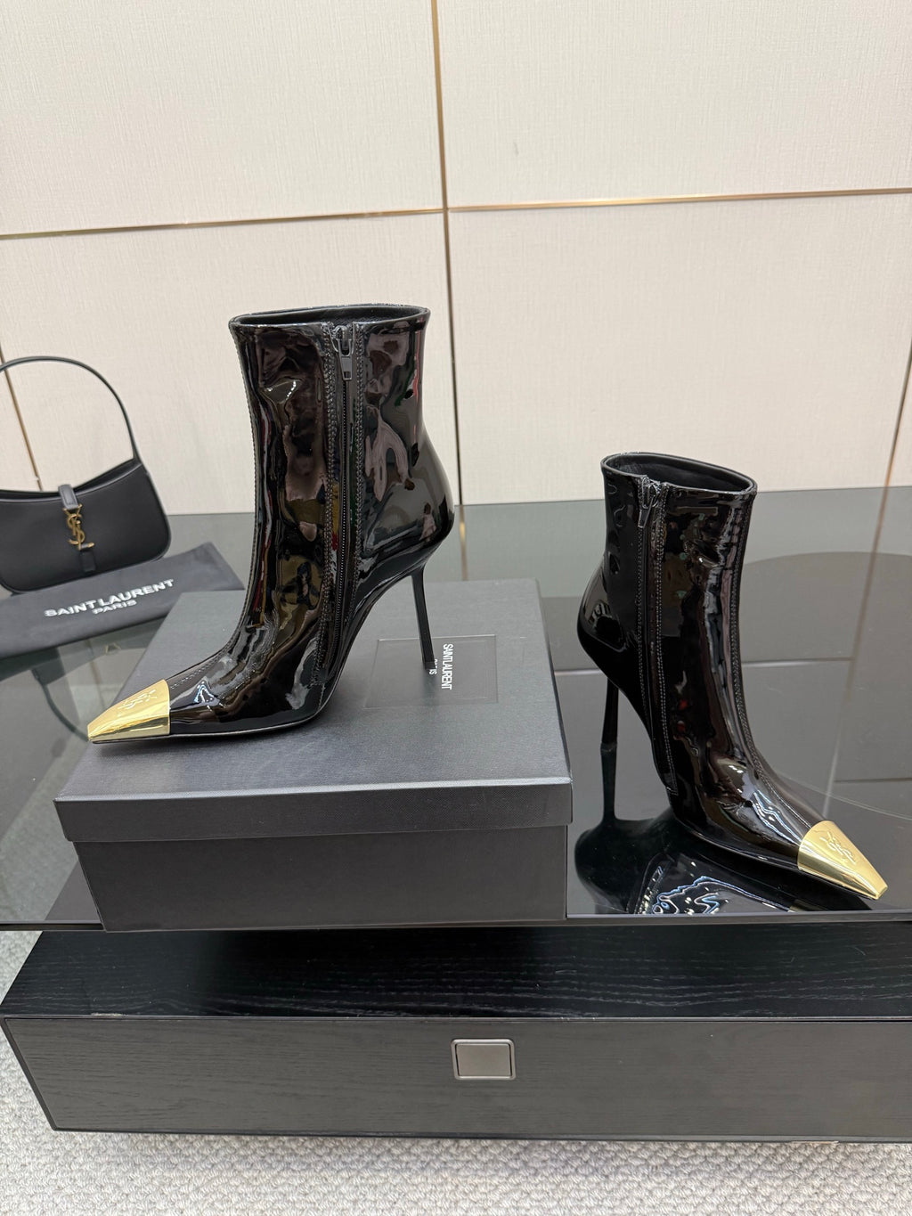 Black patent ankle boots with pointed gold heels, two-pair view on display