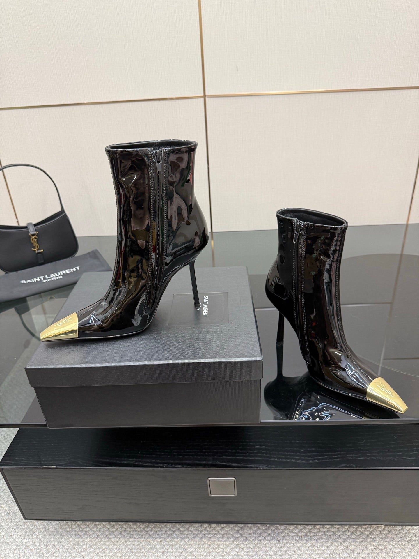 Black patent ankle boots with pointed gold heels, two-pair view on display