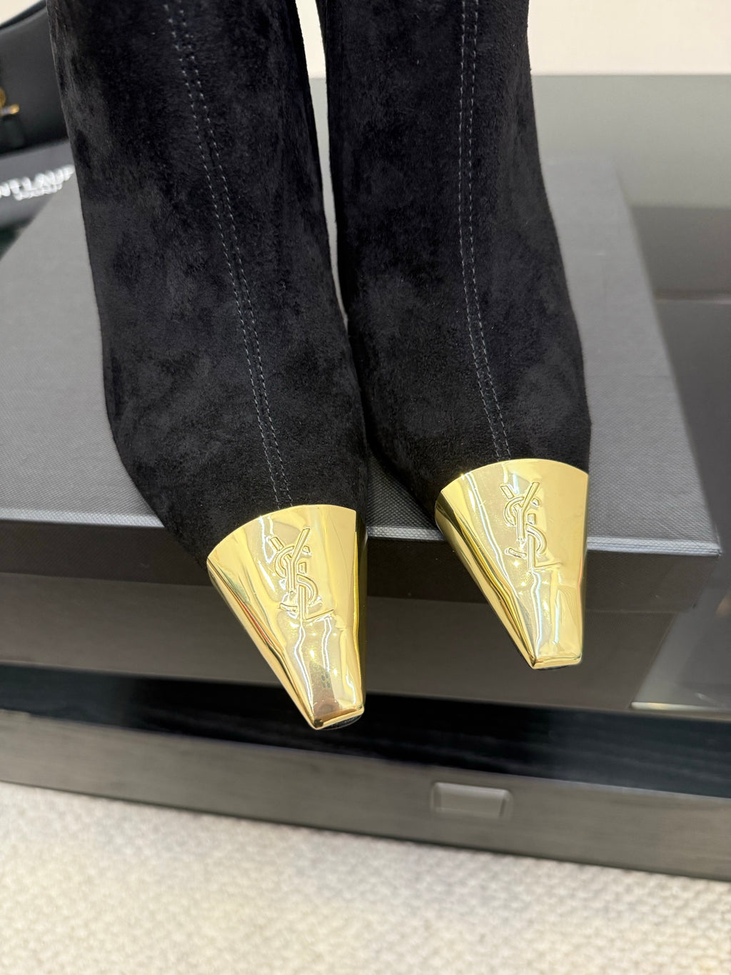YSL black suede boots close-up: pointed gold-tone toe caps and stiletto heels