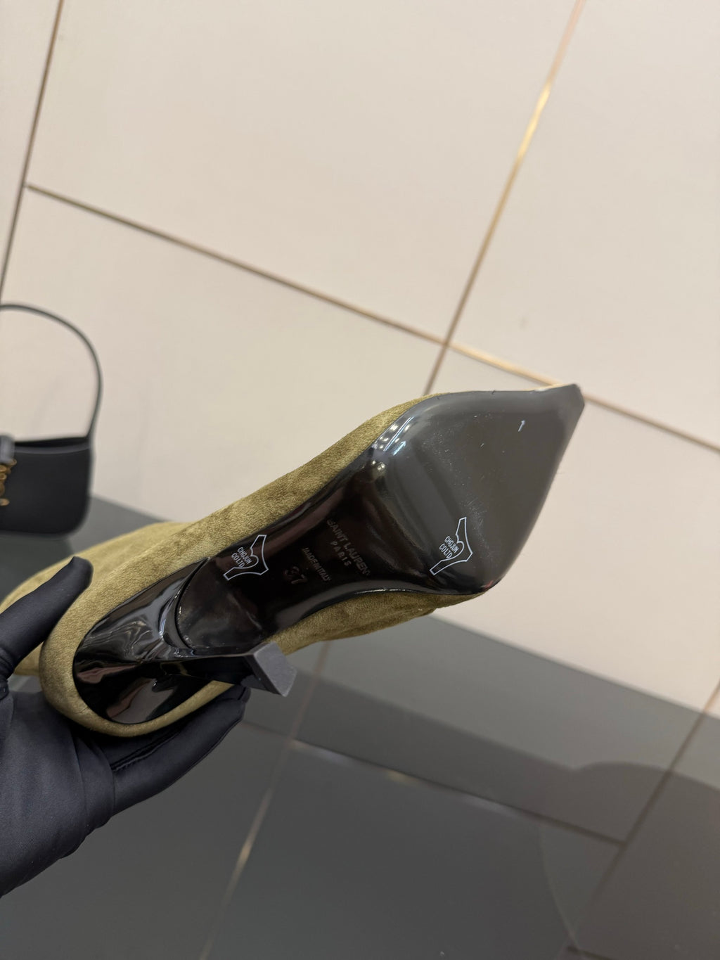 Inside view of ladies’ olive suede ankle boot showing dark lining and gold-tone crest
